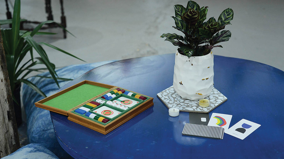 a card game and a houseplant on a round, blue table