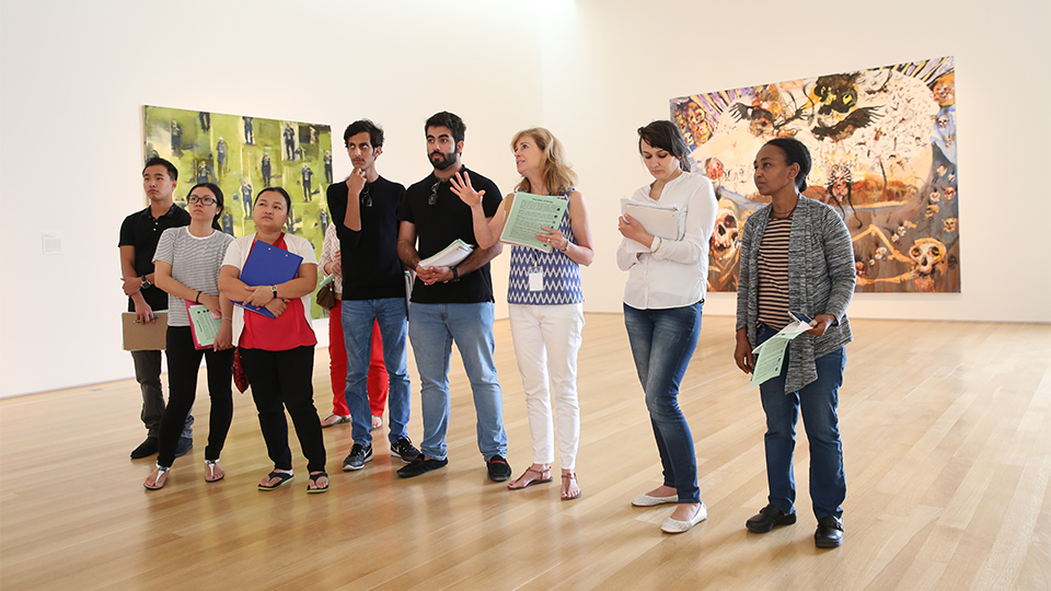 A museum docent explains a work of art to a group of people.